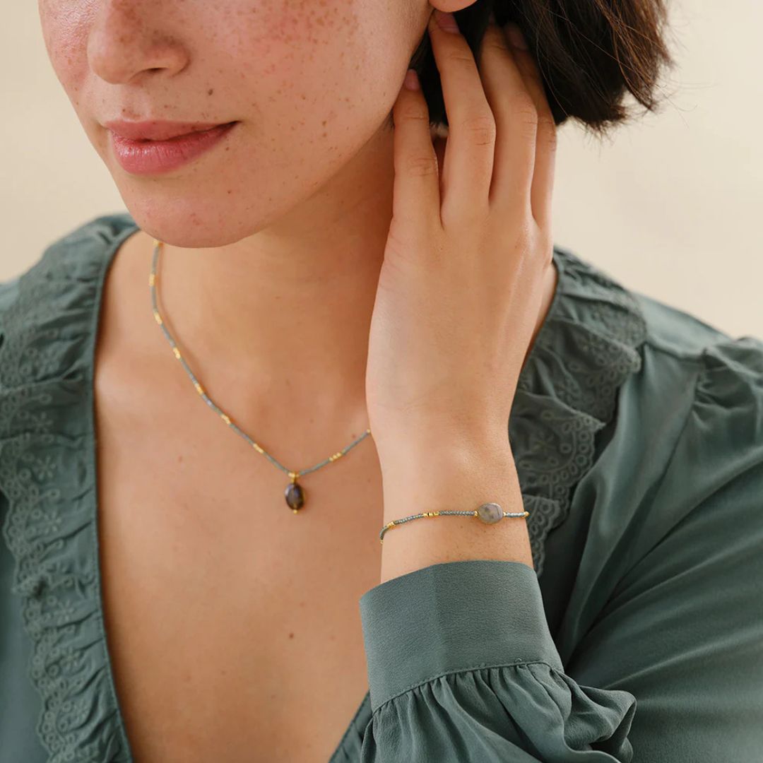 Labradoritarmbånd med glassperler i gråblå og gullfargede toner på håndledd.