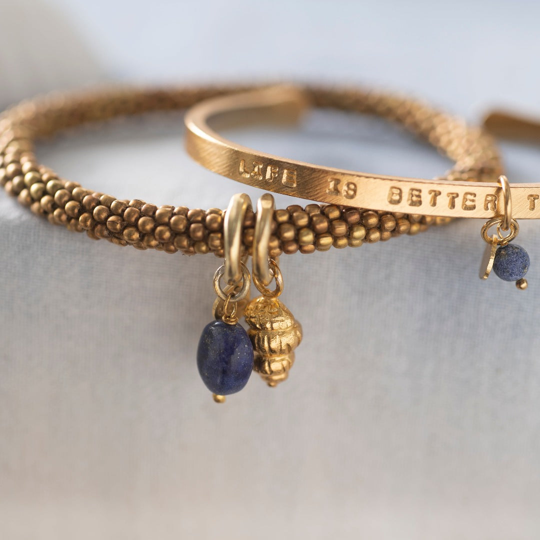 Dett kule armbåndet fra A Beautiful Story er laget av gullbelagt messing. Armbåndet har en lapis lazuli edelsten og sitatet "life is better together".  Armbåndet kan justeres etter eget ønske ved å "klemme" det. Armbåndet har en lengde på 16 centimeter. Farger kan avvike fra bildene.