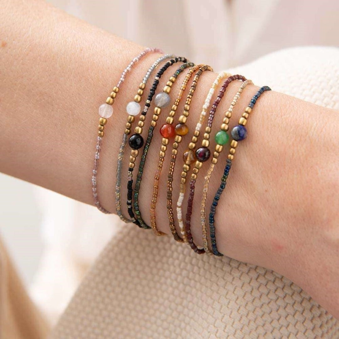 Iris Citrine armbånd er laget av bomullstråd med glass- messingperler, en liten citrin edelsten og har en justerbar glideknute. Lengden er 16- 22 cm. 