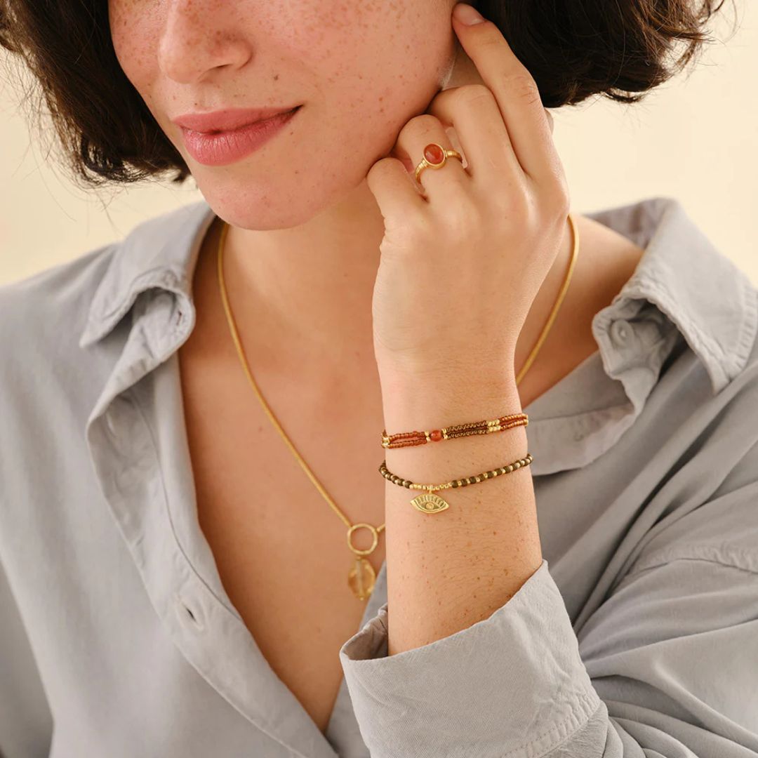Compassionate Carnelian armbånd fra A Beautiful Story, vist på håndledd med flere smykker
