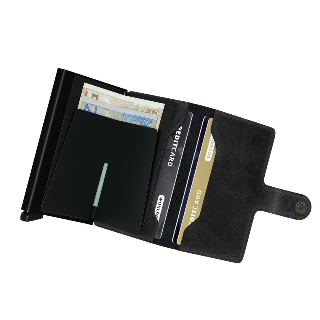 Miniwallet kombinerer det beste fra to verdener. Skallet rommer sedler, kvitteringer og kort, kortbeskytteren i aluminium lar kort skyves ut med en enkel bevegelse og beskytter dem mot bøying, brudd og uønsket trådløs kommunikasjon. St.: 65 x 102 x 21 mm. Vekt: 72 gram. Farge: MV-svart. Leveres i en gaveeske.