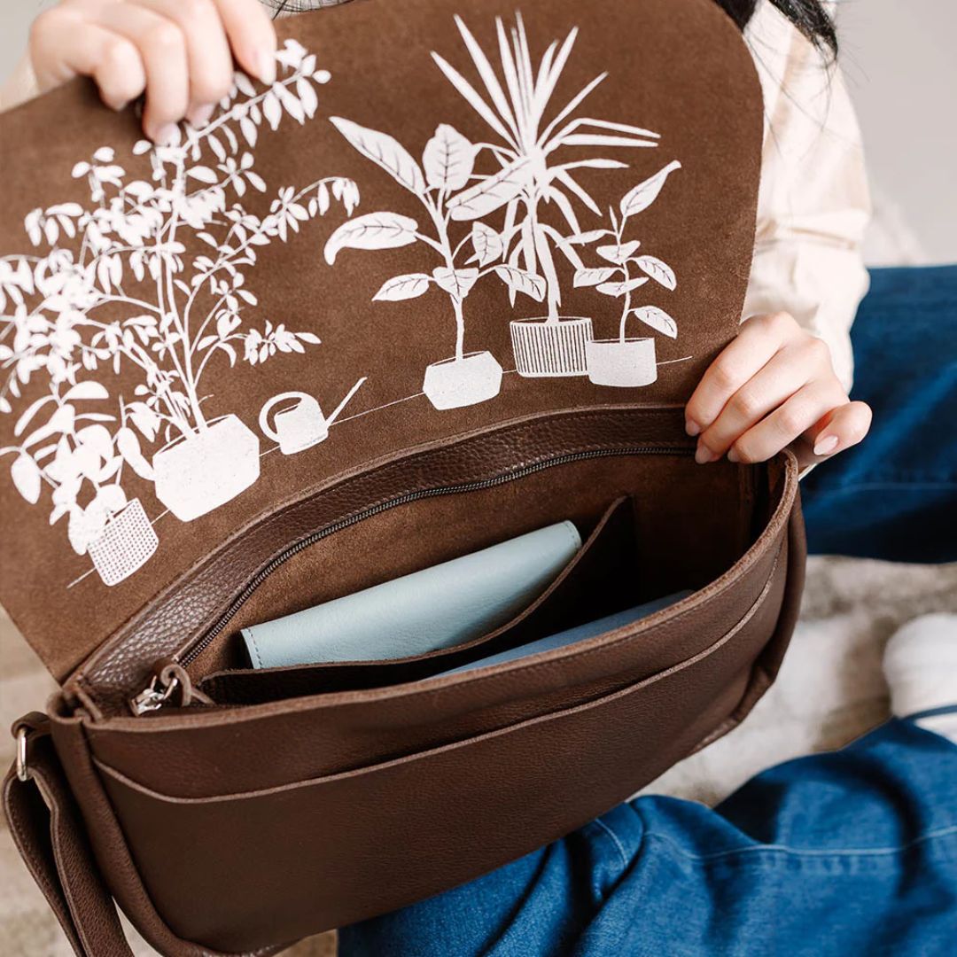 Brun skulderveske i skinn med nettbrett plassert i hovedrommet, som viser veskenes romslighet.